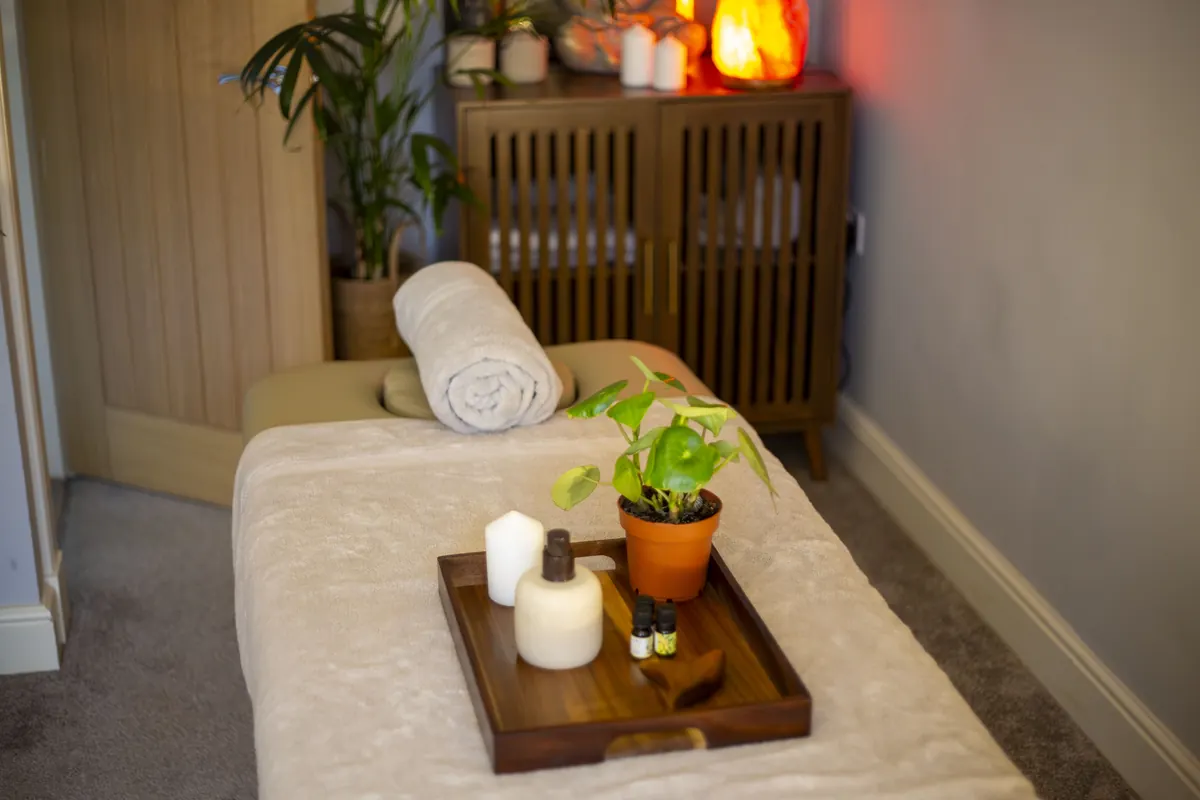 A massage table prepared with a candle and plant in the Wellness Garden treatment room